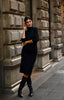 on model black dress with 3/4 length sleeves and mock turtleneck paired with boots