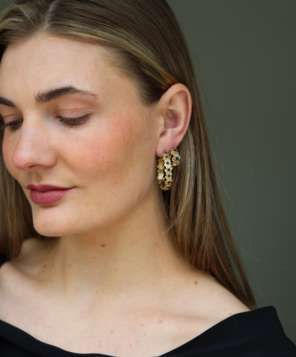Woman wearing gold hoop earrings against a neutral background
