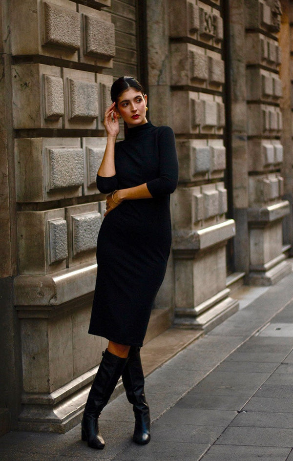 on model black dress with 3/4 length sleeves and mock turtleneck paired with boots