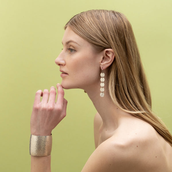 Profile shot of model with 5 disk earrings and bold modern cuff - sterling silver 
