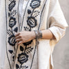 stacked bracelets on arm with embroidered ruana 